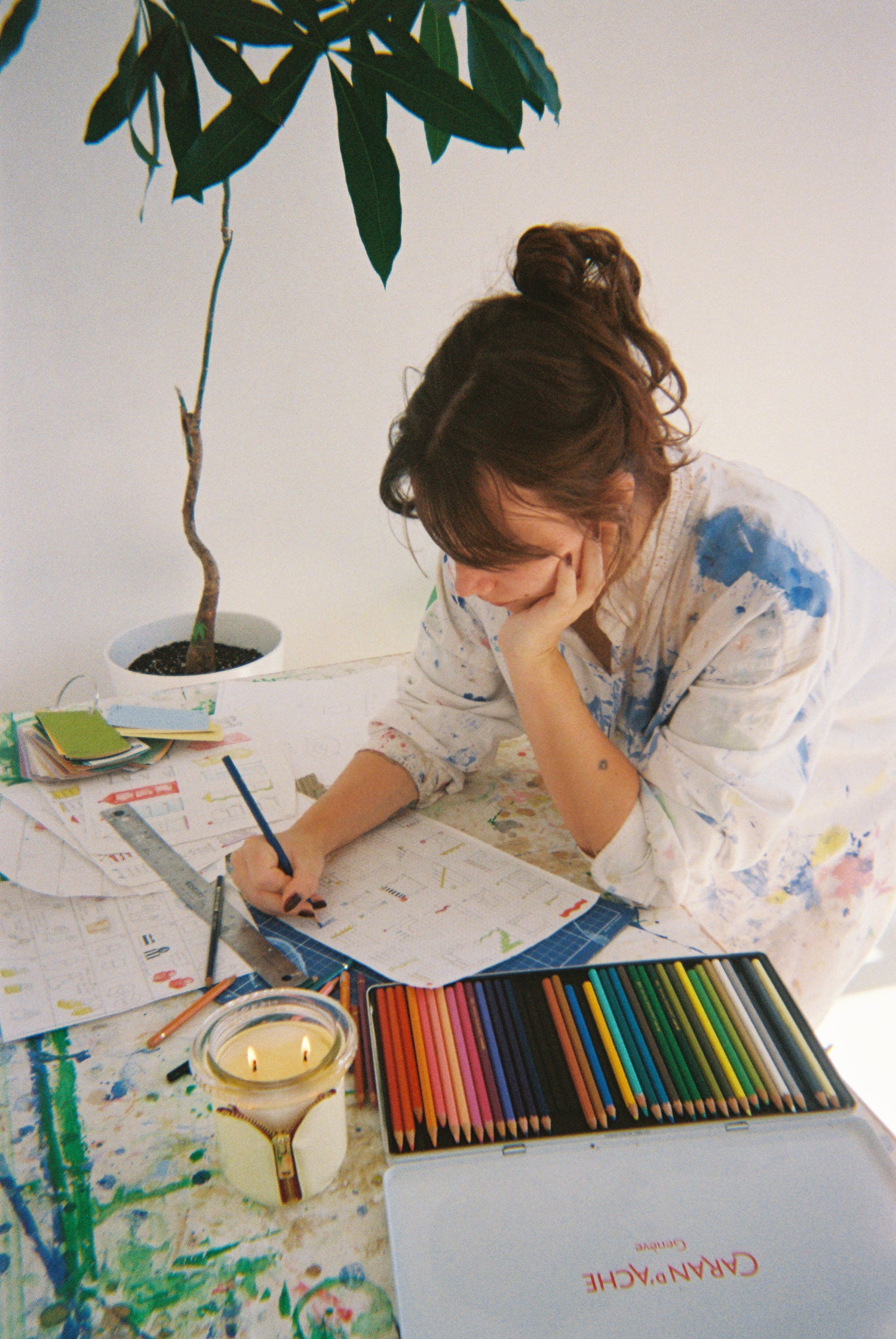 Furniture designer sophie colle sitting at a table with art supplies, including colored pencils and a notebook, being interviewed by circus candles brand 