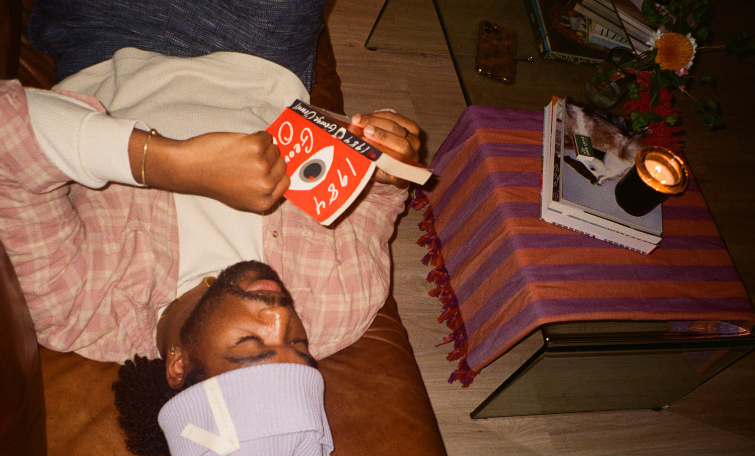 photographer joseph ross on a couch reading a book with a lamp, books and circus bound candle