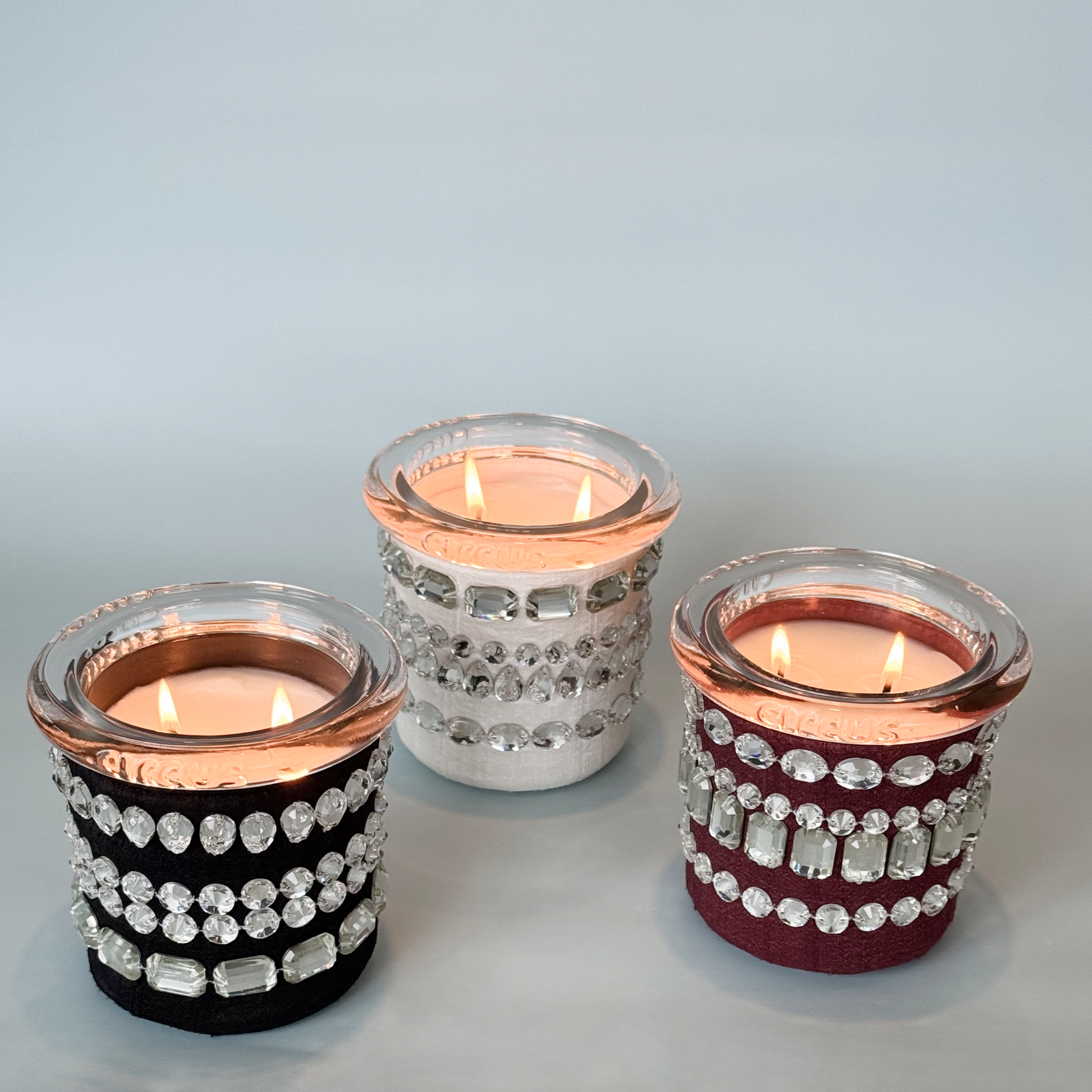 Three circus brand candles with crystals on a light gray background