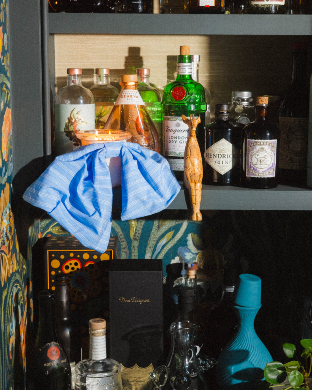 bow baby candle by circus on a bar with cocktails and vibrant designer wallpaper