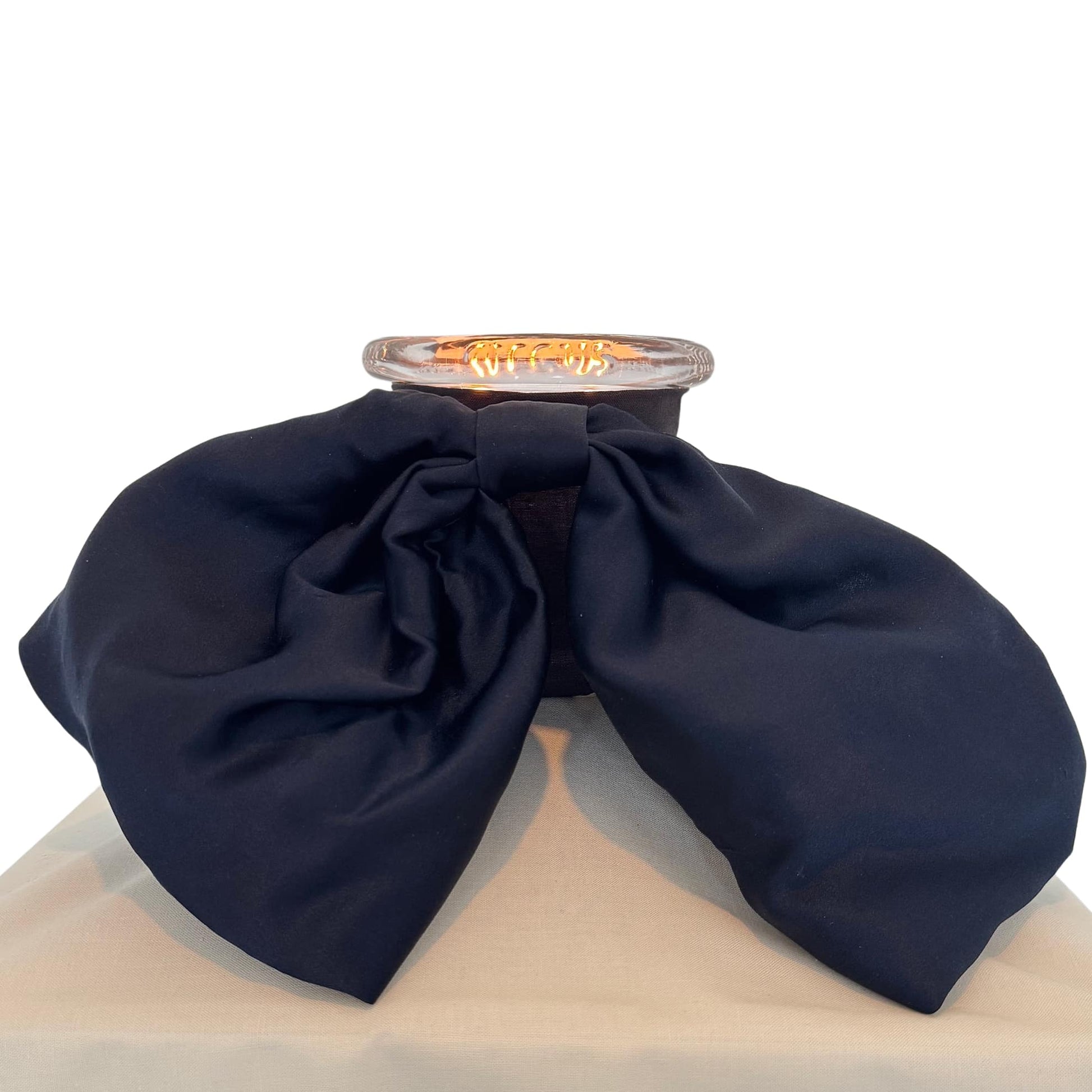 Bow Baby candle by Circus styled on khaki pedestal 