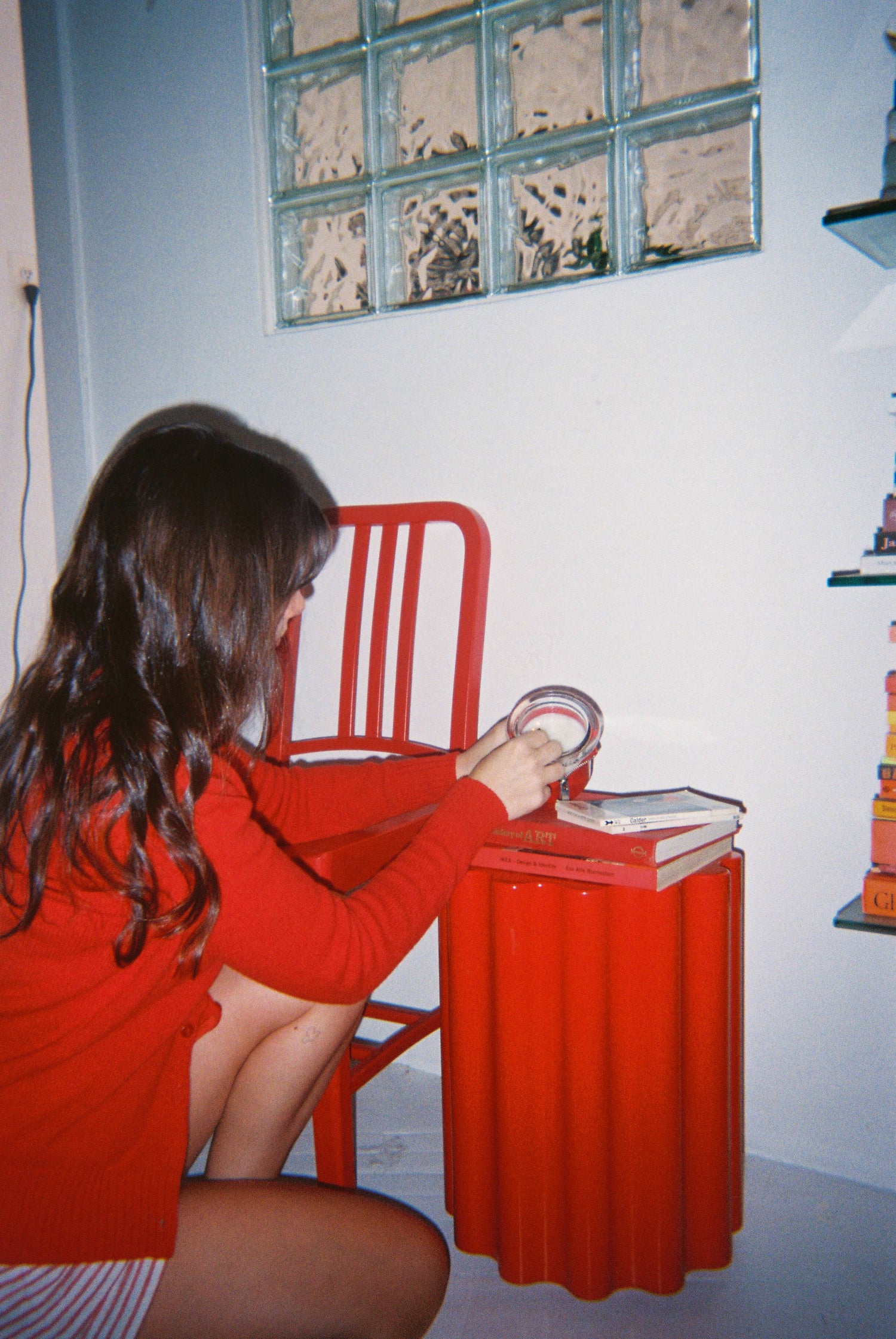 sophie colle sitting at a red table with a book and circus bound cadle in red wearing a red dress.