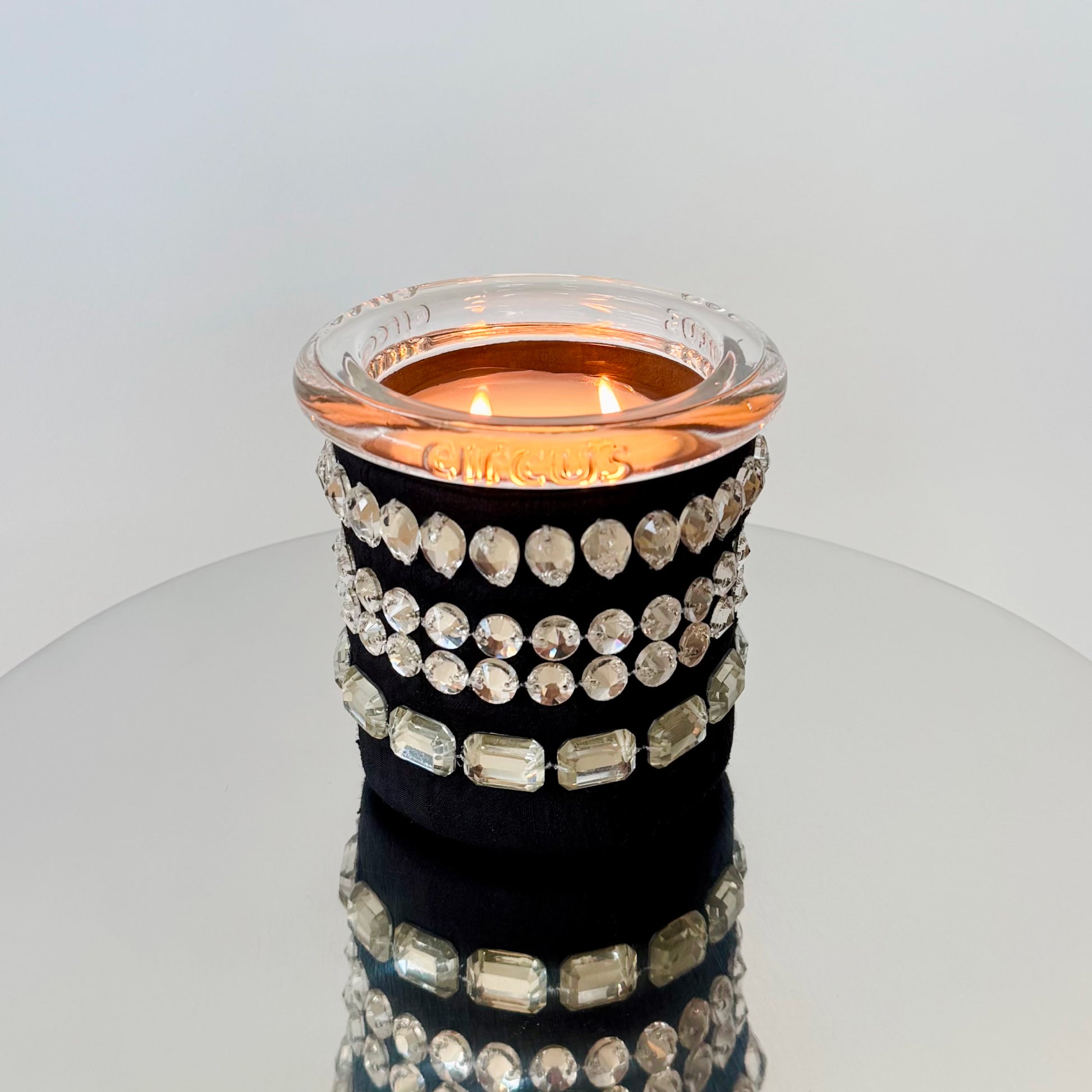 circus brand candle with crystals on a reflective surface
