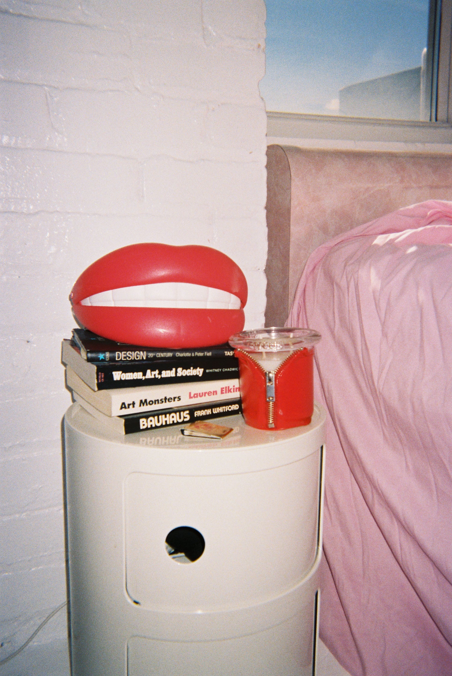 red lips and bound candle in red next to pink bed 