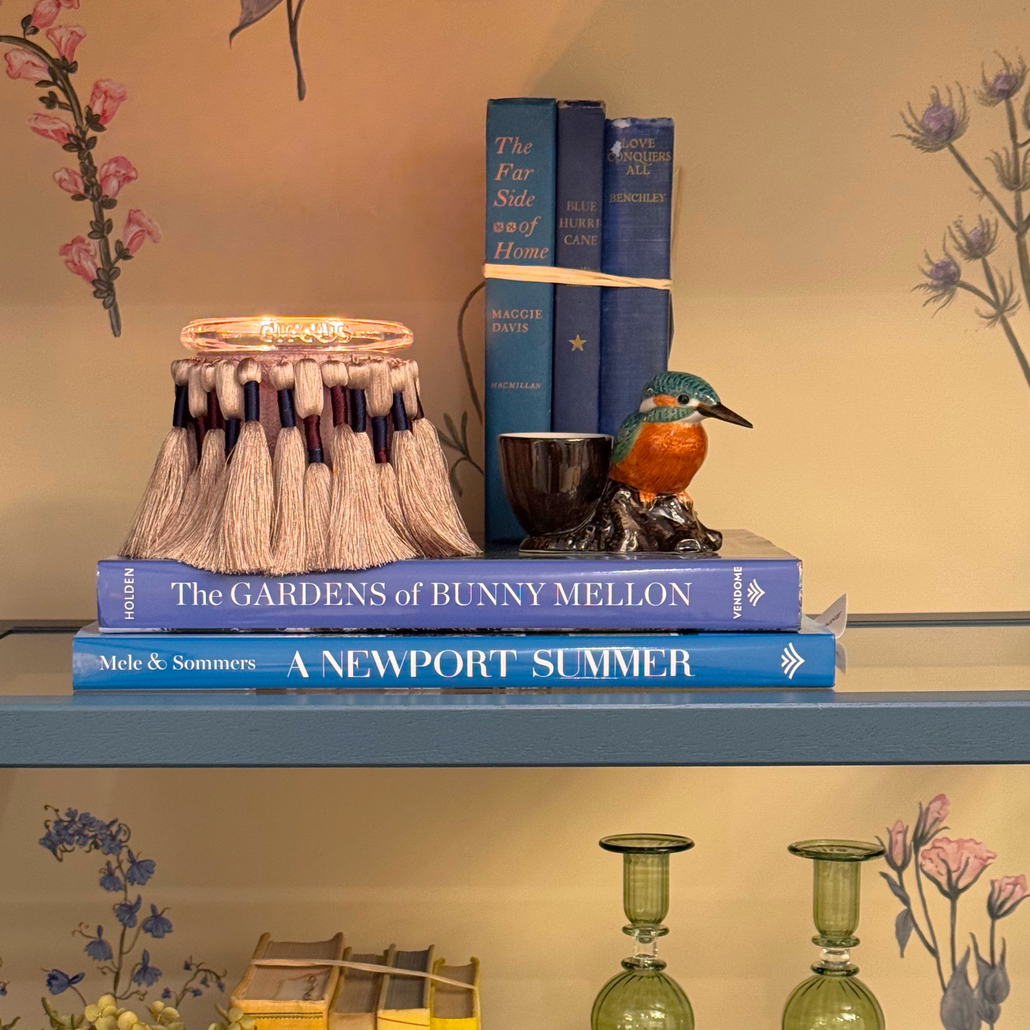 Stack of books on a shelf with decorative items and a circus candle 